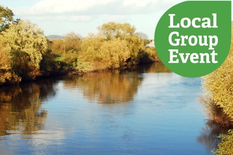 A calm wide river on a bright, lightly cloudy day, with local group event icon overlaid