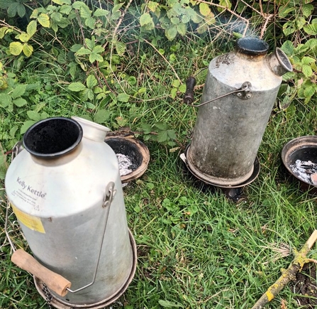 Two Kelly Kettles standing on the grass