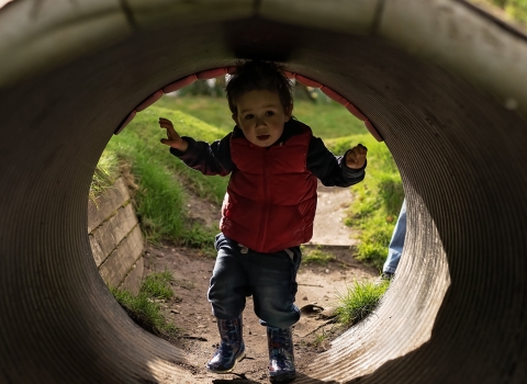 Child playing in tunnel outdoors 