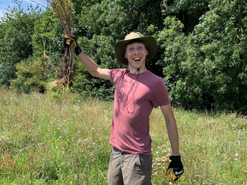 Intern Sam at Trumpington Meadows with ragwort held high