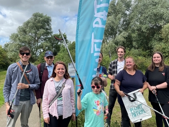 Group of people holding litter pickers next to planet patrol sign