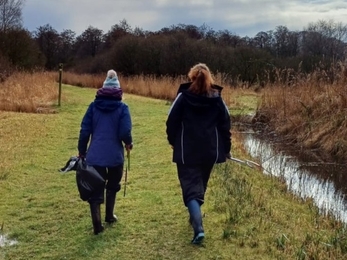 Interns walking with litter picking equipment at Woodwalton Fen