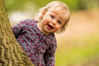 Toddler behind tree by Adrian Clarke