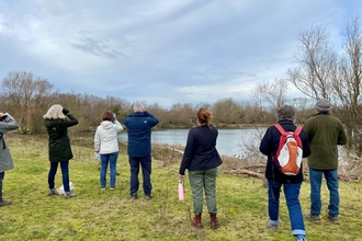 Group of people looking over a lake using binoculars