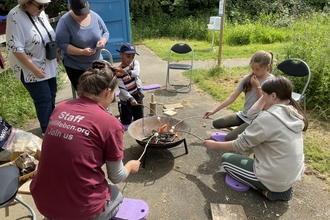 Group of children and staff member roasting marshmallows