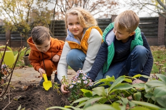 Three children in the garden planting