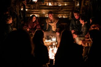 People gathered around a fire, smiling at night