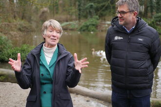 South Cambs MP Pippa Heylings talks, gesturing with her hands while standing in front of a chalk stream