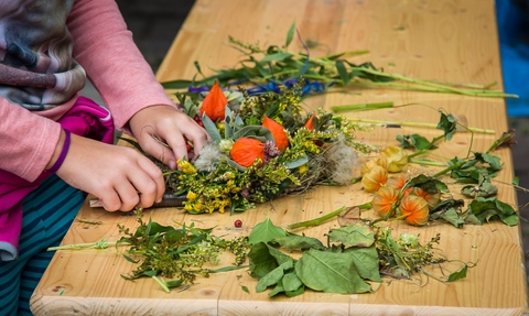 An autumn wreath in progress on a bench