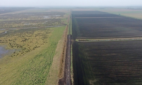Aerial view of Speechly's Farm, dark ground on one side, green, wet land on the other