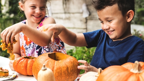 Two children carving pumpkins