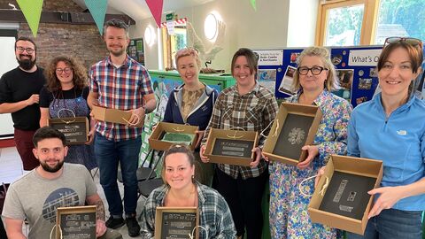 A group of adults holding boxes containing the small mammal bones they've extracted from owl pellets