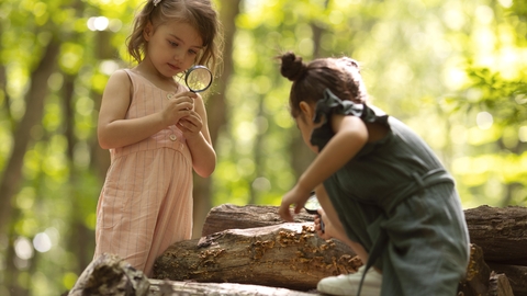 Toddlers in nature with magnifying glass