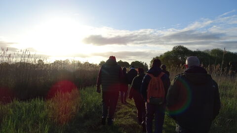 Sun rising over Woodwalton Fen, group of people walking away from camera