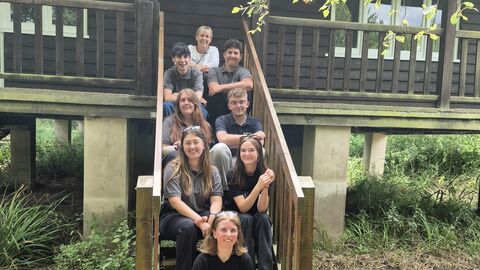 Eight young people sitting on the steps leading up to Rothechilds bungalow.
