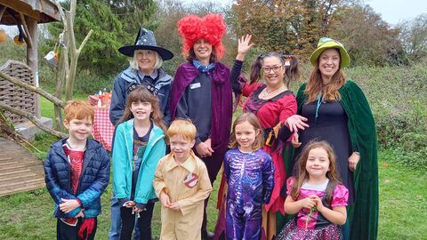 Adults and children in fancy dress stand in a nature reserve