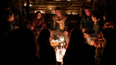 People gathered around a fire, smiling at night