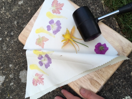 Flowers laid out on a piece of fabric with a mallet laid nearby, ready to use