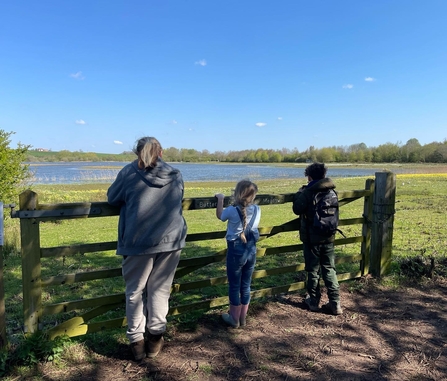 3 young people looking out onto the butterfly meadow at Summer Leys