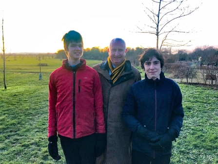 Two members of the Young Peoples Forum, standing in a frosty field with Daniel Zeichner MP, all smiling at the camera