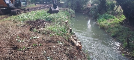 A digger finishing work strengthening a bank of a river
