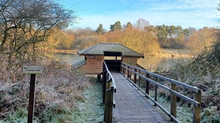A view of a hide on the water front, from the top of a boardwalk leading down to it.