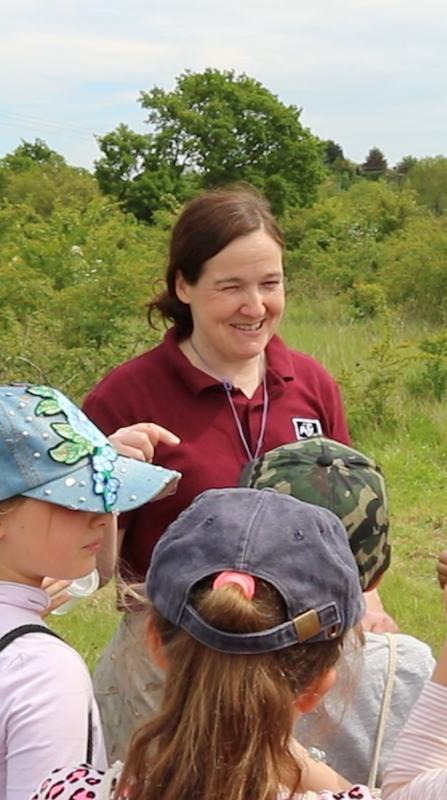 Debbie addresses a group of children in a field