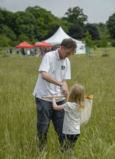 A young Emma stands with her dad in Trumpington Meadows, holdaing a sweep net.