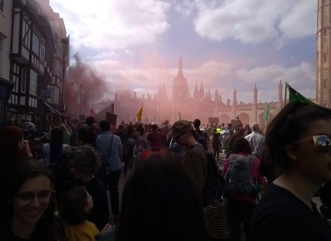 The climate strike culminates outside Trinity College, Cambridge, with symbolic smoke hanging in the air