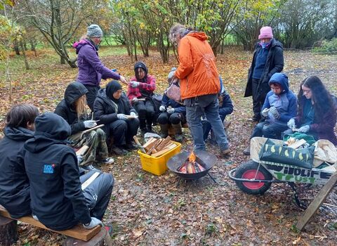 Group of young people sat around a campfire with WTBCN staff members