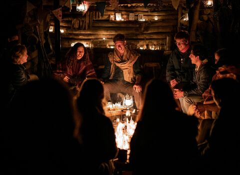 People gathered around a fire, smiling at night