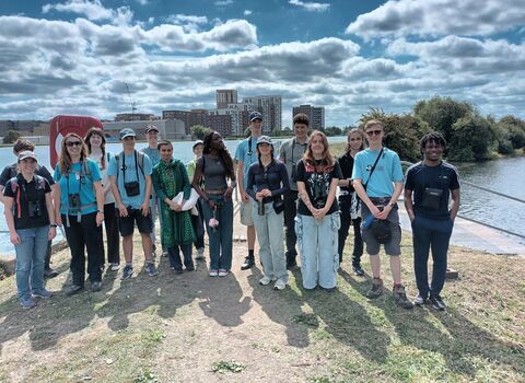 A group of diverse young people stood together, gathered infront of a body of water
